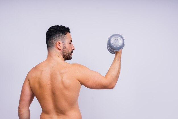 Athletic man doing exercises with dumbbell at biceps on white background strength and motivation