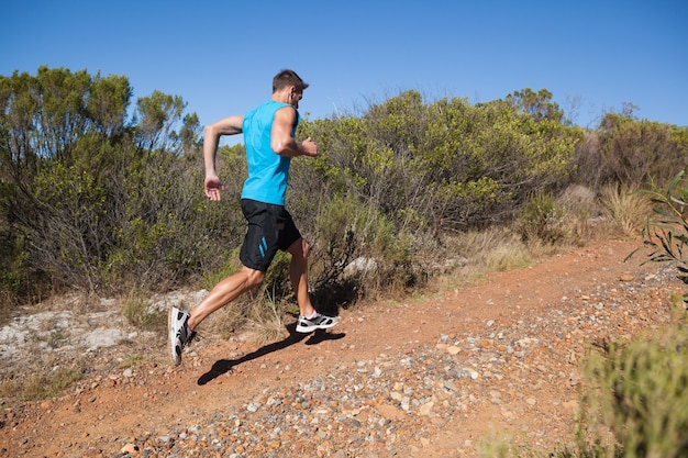 Athletic man jogging up country trail