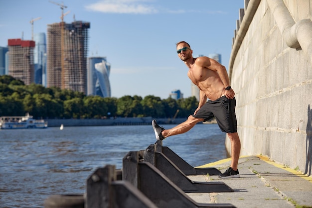 Athletic man running and doing functional workout outdoors Sportive adult male with sportswear training in a city