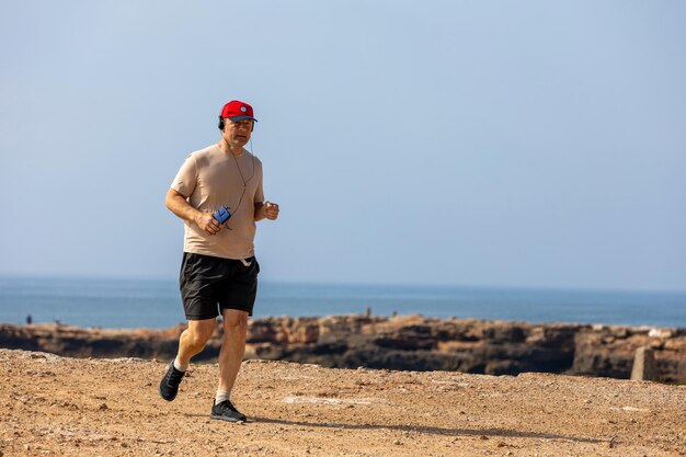 Athletic man running in park with headphones on sunny summer day Healthy lifestyle Active adult men is jogging