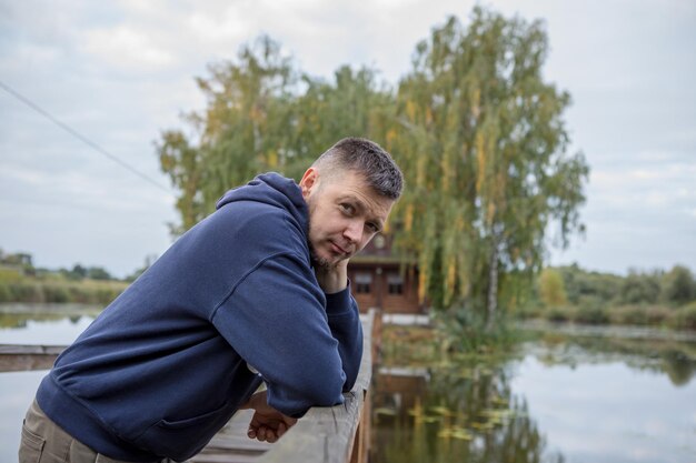 Athletic man standing on city bridge over river and looking at camera