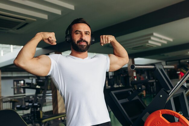 Athletic man in a white shirt shows off his muscles in the gym