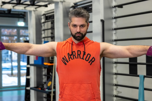 Athletic man with beard working on his biceps and triceps lifting dumbbells training arms in the gym