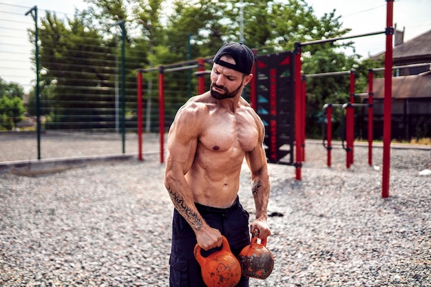 Athletic man working out with a kettlebell at street gym yard