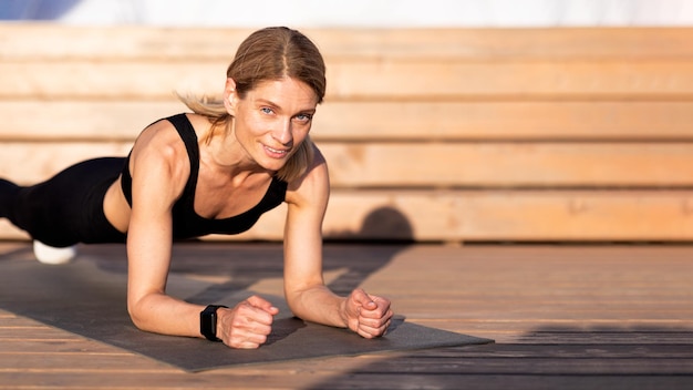 Athletic Middle Aged Female Training Outdoors Making Plank Exercise