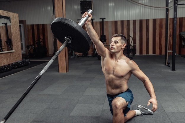 Athletic muscular man exercising with barbell in modern health club. Bodybuilding and Fitness