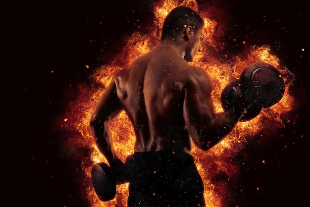 Athletic muscular man training biceps at the gym with fire effect