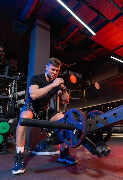 Athletic muscular sportsman doing exercise Strong young man hard training in gym