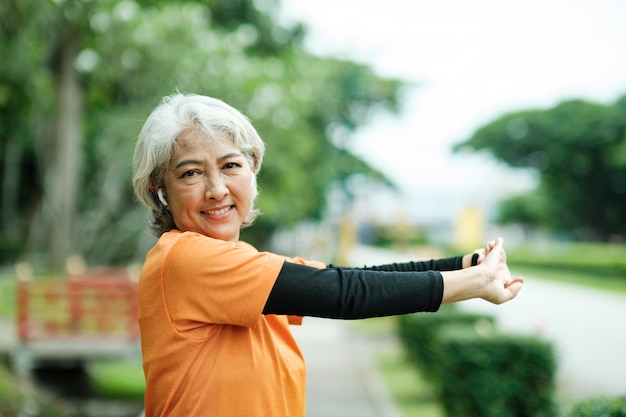 Athletic Senior woman stretching arms in park