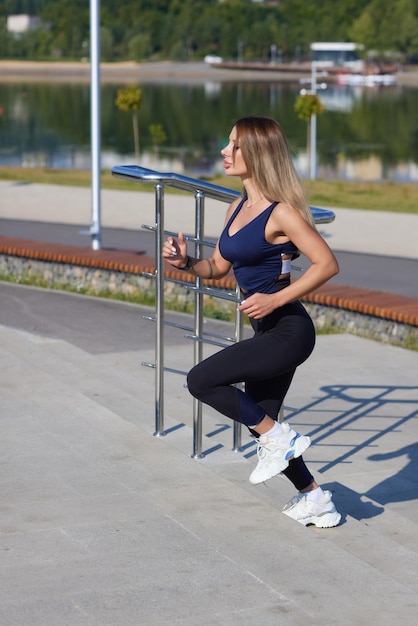 Athletic slim woman on a sunny day runs along the embankment or park