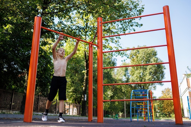 An athletic teenager prepares to perform an exercise Street workout on a horizontal bar in the school park