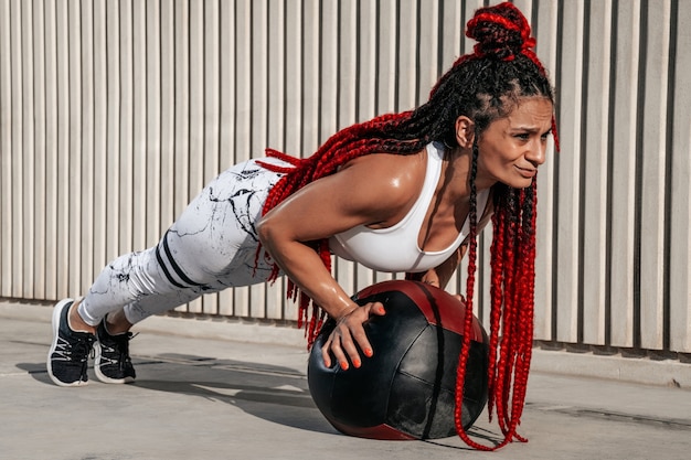 Athletic woman doing exercise push ups with med ball. Strength and motivation.Photo of sporty  woman in fashionable sportswear