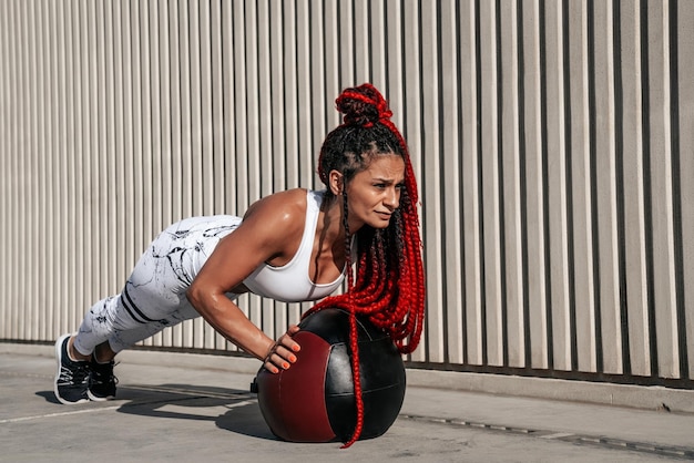 Photo athletic woman doing exercise push ups with med ball strength and motivationphoto of sporty woman in fashionable sportswear