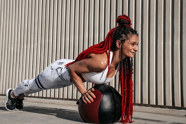 Athletic woman doing exercise push ups with med ball Strength and motivationPhoto of sporty woman in fashionable sportswear