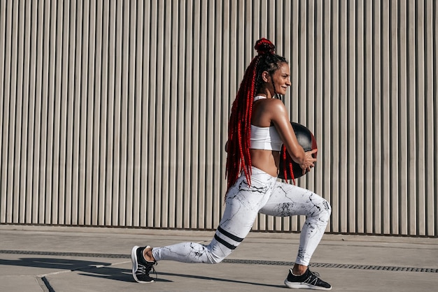 Athletic woman doing Lunge exercises with med ball Strength and motivationPhoto of sporty woman in fashionable sportswear