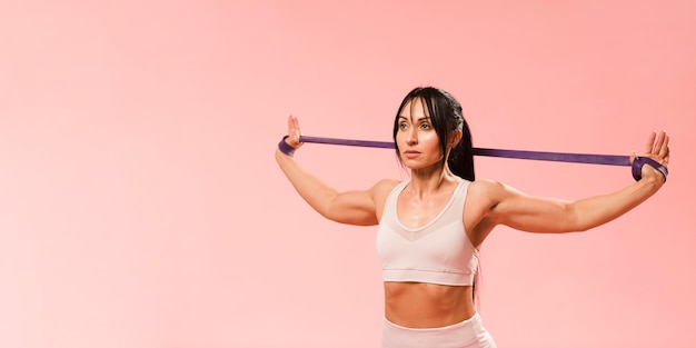 Athletic woman in gym outfit stretching resistance band