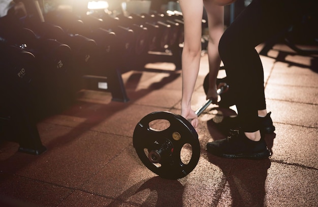 Athletic woman holding dumbbell during cross training at fitness gym. Health and muscles flexing.