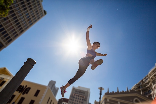 Athletic woman jumping off the bollard