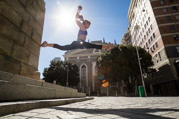 Athletic woman jumping off the stairs and doing split in the air