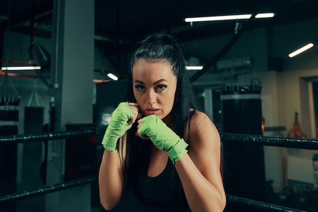 Athletic woman standing prepared for fight with boxing bandages on hands during box training