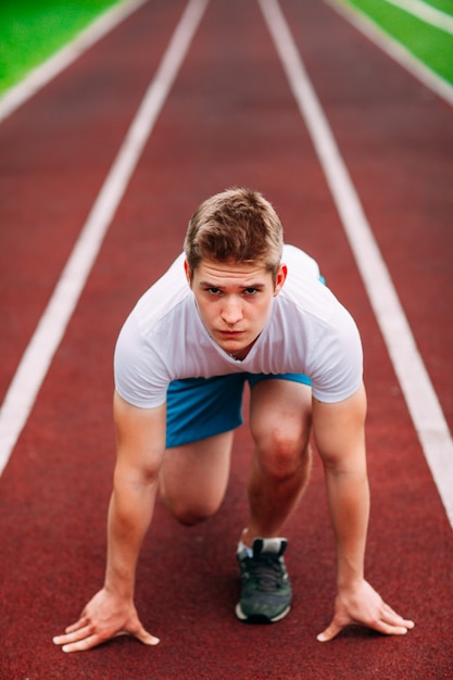 Athletic woman on track starting to run. Healthy fitness concept with active lifestyle.