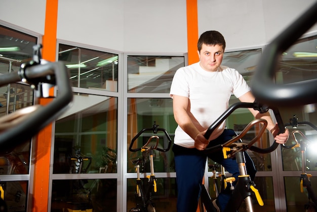 Athletic young man having stationary bike workout