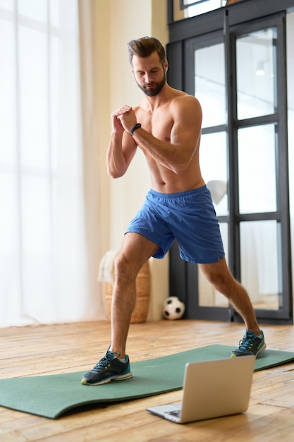 Athletic young man using notebook during home workout