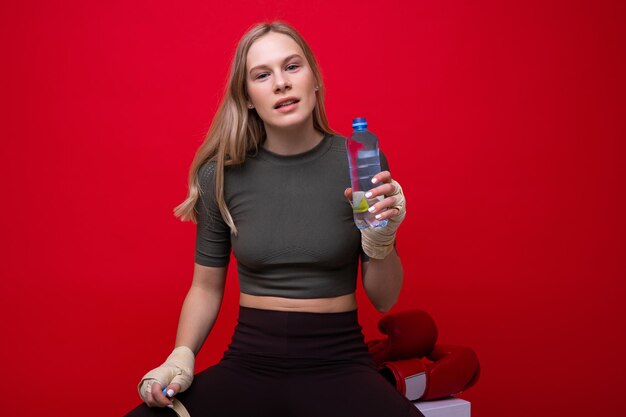 Athletic young woman drinks water after boxing training