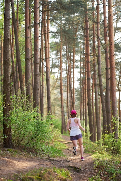 Athletic young woman in pink sneakers run in spring forest