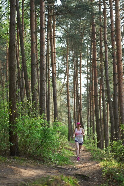 Athletic young woman in pink sneakers run in spring forest