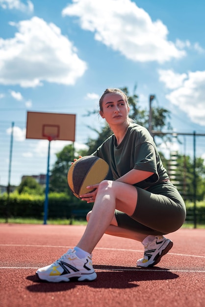 Athletic young woman posing with a ball on the court