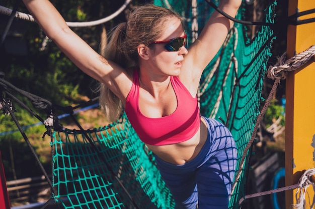 Athletic young woman working out at the rope training camp