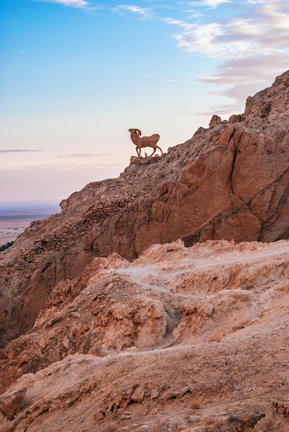 Atlas Mountains with a statue of a ram on a mountainside against the backdrop of a sunset sky