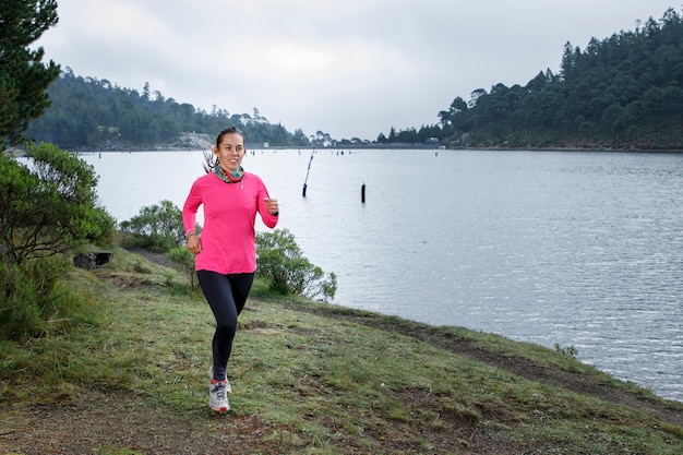 Atleta corriendo al aire libre cerca de un lago con montanas al fondo