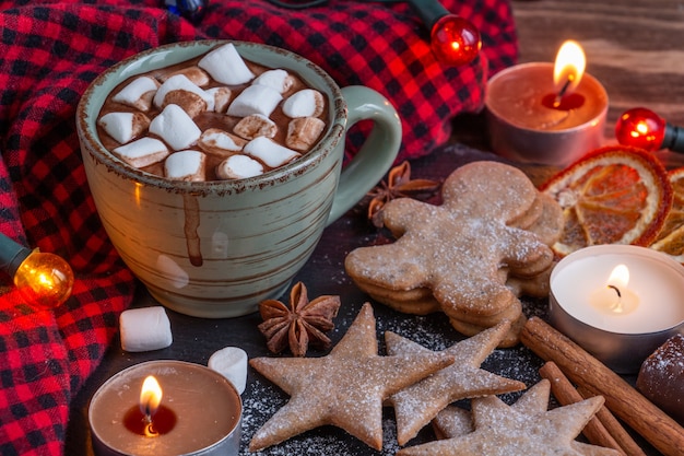 Atmospheric christmas composition a cup of cocoa with marshmallows candles gingerbread cookies sweet...