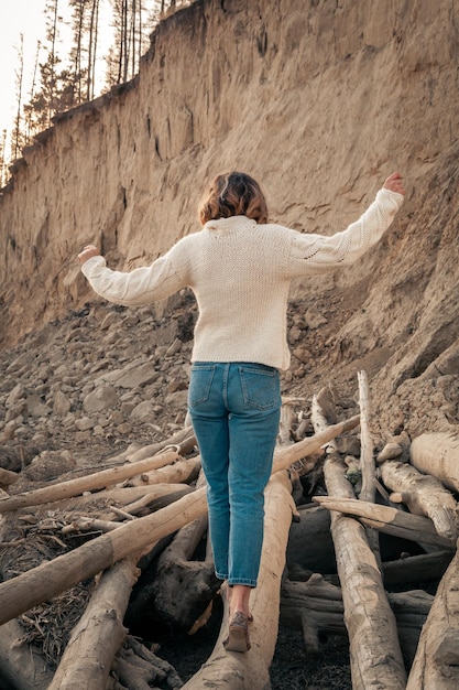 Atmospheric lifestyle photo of young beautiful woman white knit sweater made of natural wool and jeans in on the beachThe concept of the unity of women and nature peaceful mood ecofriendly life