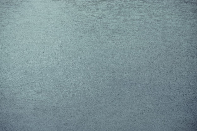 Atmospheric nature background of azure water in mountain lake. Scenic nature backdrop with rain circles on water surface. Beautiful minimalist fragment of blue mountain lake with rainy circles.