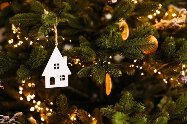 Atmospheric photo Christmas decoration with a house figure on a Christmas tree with lights and balls.