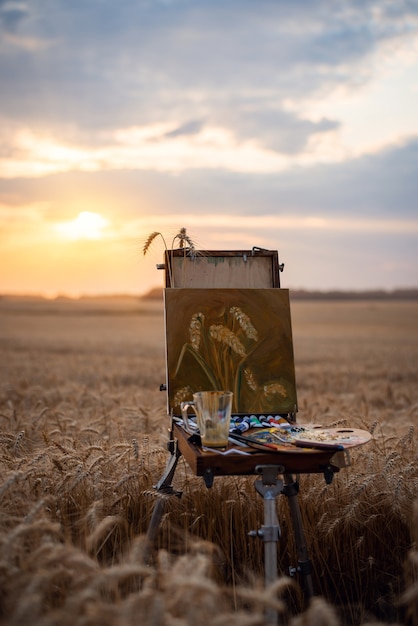 Atmospheric photo of a ready still life painting on an easel in the field of rye