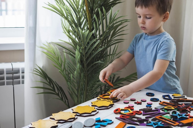 Attentive cute baby boy learning geometric figure shapes playing multicolored wooden construction