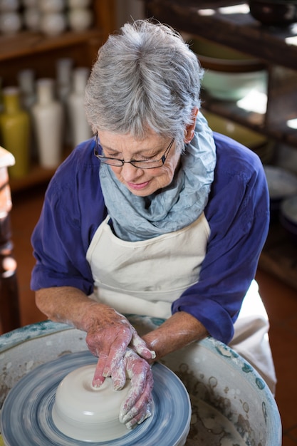 Attentive female potter making pot