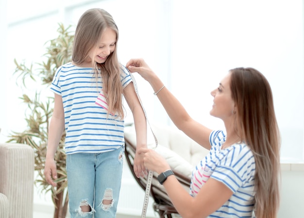 Attentive mother and daughter make measurements for new clothes