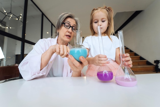 Attentive old grandma assist grandkid in funny scientific research