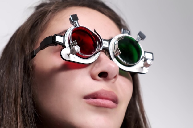 Attentive optometrist examines a beautiful female patient checks her vision in an ophthalmological clinic Closeup of a doctor inserting a greenred lens into a trial frame