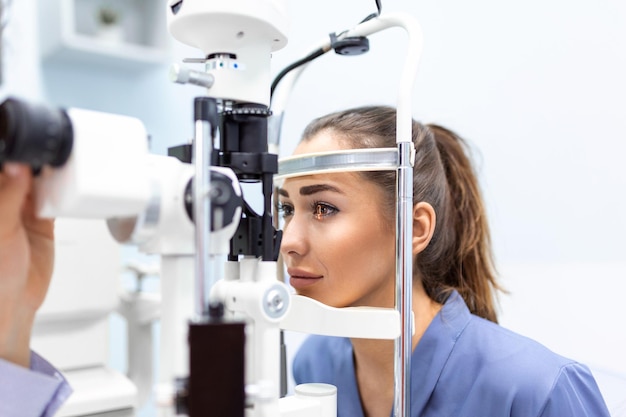 Attentive optometrist examining female patient on slit lamp in ophthalmology clinic Young beautiful woman is diagnosed with eye pressure on special ophthalmological equipment