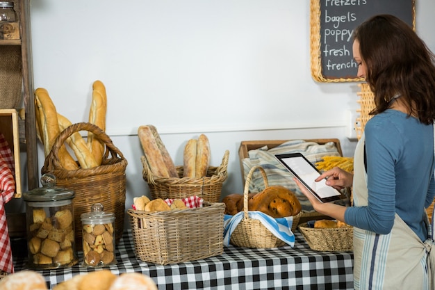 Attentive staff using digital tablet at bakery counter