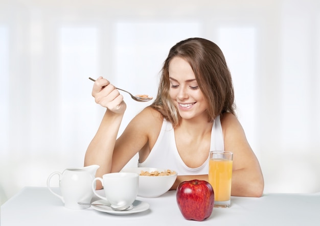 Attracive young woman enjoying tea and fruits on breakfast