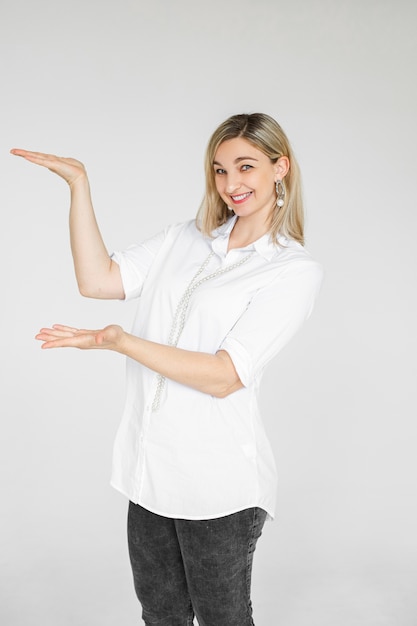 Attracrive caucasian woman with blonde hair smiles and shows something isolated on white space