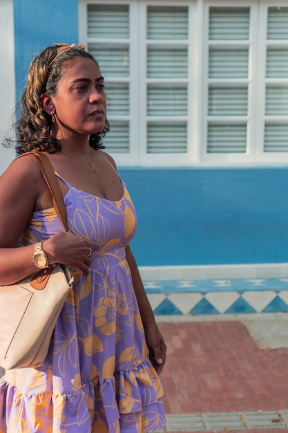 Attractive 40-year-old woman in dress and handbag walking down the street