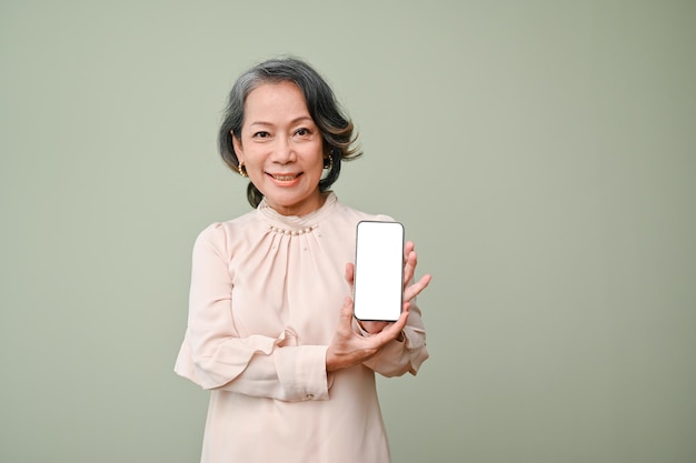 Attractive 60s senior asian woman showing a smartphone white screen mockup isolated background